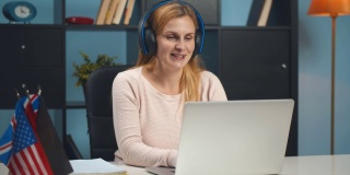 戴着耳机的女学生在家里的电脑上在线学习语言