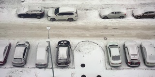 城市的冬天下雪了。停车场的俯视图。路被雪覆盖，车被雪覆盖