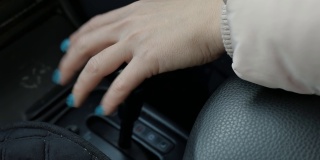一个有绿色指甲的女人的手在一辆车里开关变速杆