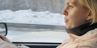一个年轻的白人女子在冬天开着一辆车行驶在下雪的高速公路上