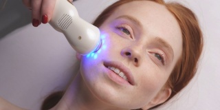 一个有吸引力的女人在美容诊所接受面部皮肤语音电泳程序。美容师在面部移动操作器