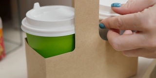 涂着绿色指甲的女人的手盖上了装卡布奇诺的纸杯