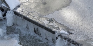 这是一张可怕的照片，冬天结冰的水流过一个小水坝。