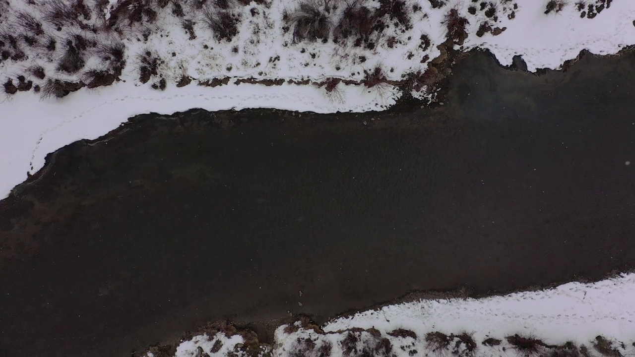 无人机在冬季暴风雪下的山区河流上方拍摄