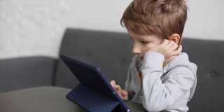 可爱的小男孩用垫子。孩子在家里玩数码平板电脑。孩子们的自由时间、科技和互联网