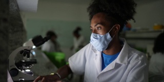 一名年轻男子在实验室使用笔记本电脑的肖像——使用口罩