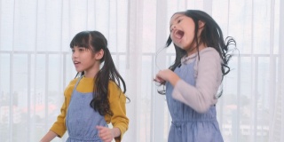 两个年轻的亚洲女孩在家里一起跳舞。