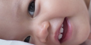 婴儿的特写:喝完奶瓶里的牛奶后，婴儿眨着眼睛微笑。孩子眨眼。娃娃脸开心的笑。亚洲的孩子。