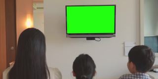 幸福的一家人坐在家里看彩色电视