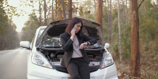 一名亚洲妇女打电话要求维修车辆在路上抛锚