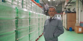 高级亚洲华人仓库工厂经理，留着胡子，双手插在口袋里，面带自信的微笑看着相机