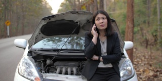 一名亚洲妇女打电话要求维修车辆在路上抛锚