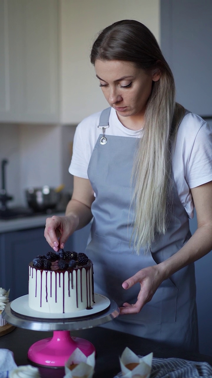 年轻可爱的女人糕点厨师准备生日蛋糕装饰在家里的厨房浆果小生意，自制糕点厨师视频高清慢动作
