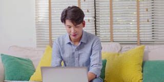 企业家英俊的商业亚洲男人穿着休闲工作在笔记本电脑桌上，接手机与客户交谈，得到要求或订单微笑和幸福的工作在家里