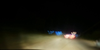 从挡风玻璃肮脏的车里看到的夜间印度高速公路的超短镜头。车里的视角。汽车留下轻轨。汽车在夜间的高速运动