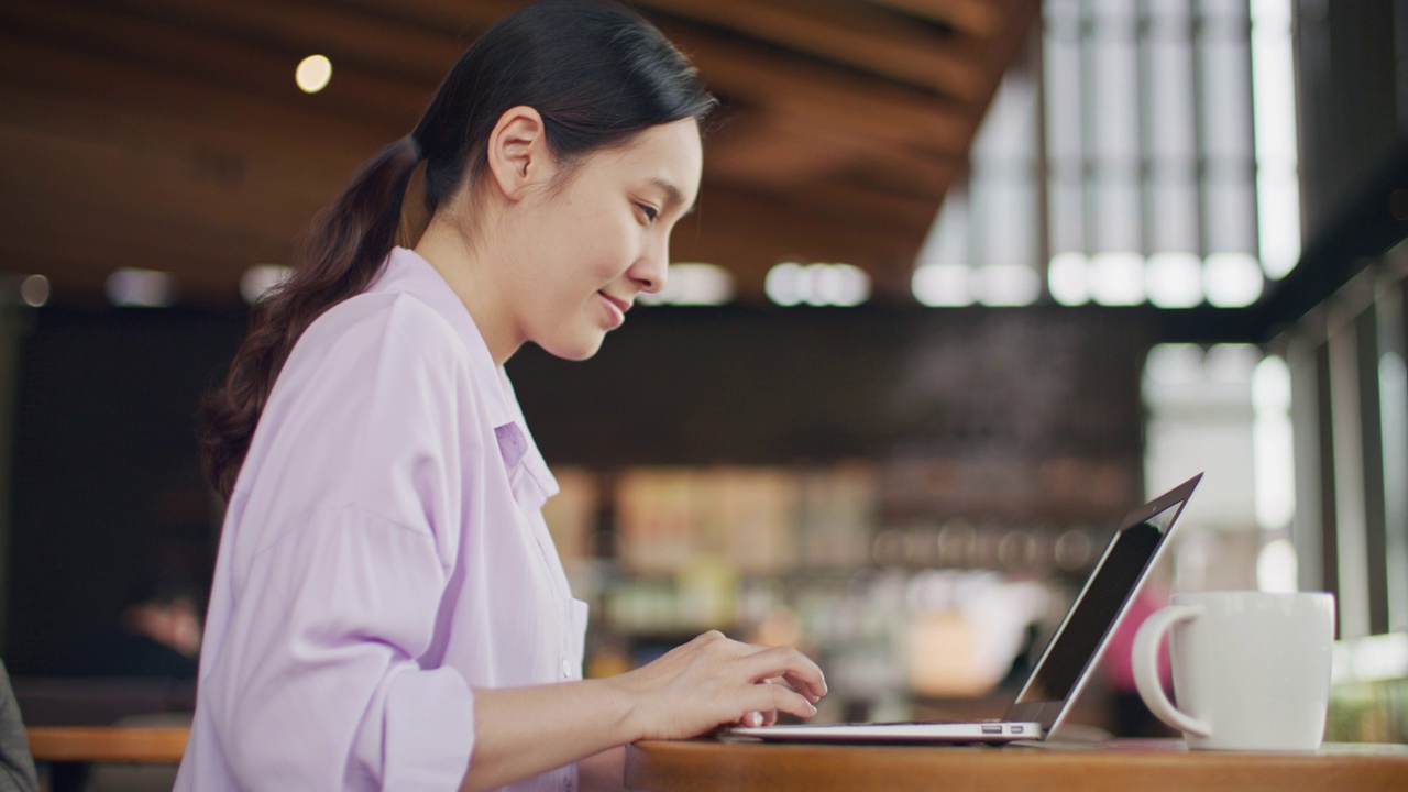 一个亚洲女人在咖啡厅用笔记本电脑工作