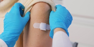 护士给接种疫苗的妇女贴医用贴片