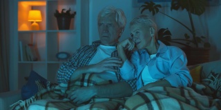 幸福微笑的老夫妇在家里看电视