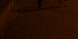 一个男人撑着伞走在人行道上，两脚沐浴在黑暗中