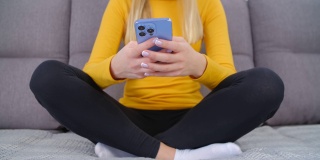 年轻女子使用手机进行在线交流。白人女性在现代智能手机上的社交媒体应用程序上打字。坐在沙发上的人在发短信