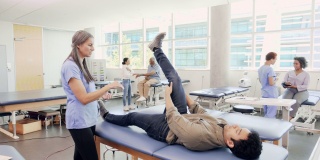 自信的女性理疗师协助男性患者进行腿部锻炼