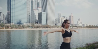运动女性在城市跑步前戴着无线耳机伸展肌肉，做热身运动。