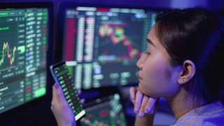 年轻的女商人使用多个电脑屏幕学习和交易加密货币和股票市场和交易所，同时工作到深夜视频素材模板下载