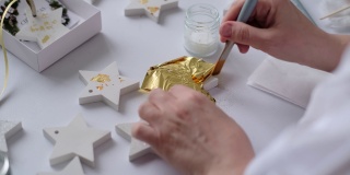 应用金箔。女艺术家用一片金箔装饰着这幅金色的石膏工艺品