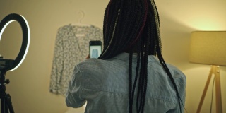 一名女子正在用智能手机拍摄一件衬衫，用于出售或捐赠衣服。
