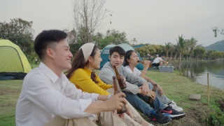 群亚洲四青年朋友男女在河边野餐野营，他们有说有笑，喝着庆祝欢呼啤酒。视频素材模板下载