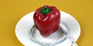 减肥的概念。一个红辣椒被包裹在一个卷尺里，卷尺延伸到框架外