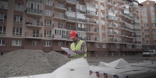 图为，在住宅建筑施工现场，一名戴着头盔和头盔的创新施工主管正在核对材料和材料数量。建筑督察工作