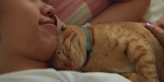 亚洲妇女睡觉和拥抱小猫小猫在家里的床上。