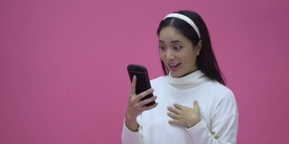 美丽的亚洲女性微笑着用智能手机网购，为成功而兴奋