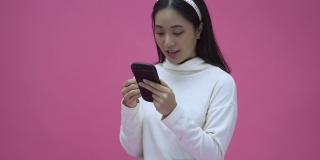 美丽的亚洲女性微笑着用智能手机网购，为成功而兴奋