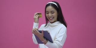 美丽的亚洲女性微笑着使用平板电脑和信用卡购买网上购物