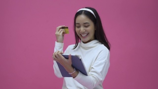 美丽的亚洲女性微笑着使用平板电脑和信用卡购买网上购物视频素材模板下载