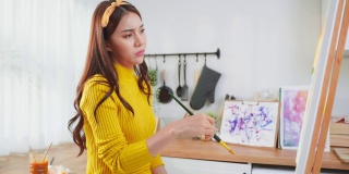 亚洲年轻有才华的女艺术家在画板上作画。吸引人的美丽女性画艺术图画，创作艺术品水彩画和画笔享受创作活动在家里。
