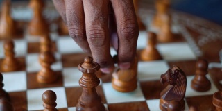 国际象棋的特写镜头，一个印度人的手在背景移动国际象棋的棋子。国际象棋的背景。成功商人的概念，战略思维。