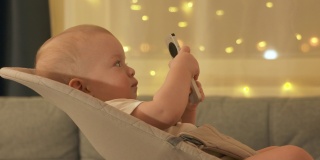 白人小婴儿在家里看电视，可爱的小蹒跚学步的孩子拿着电视数字媒体播放器的遥控器。
