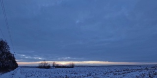 乡村田野上的冬季日出景观，时间流逝。厚厚的云层飞了过去，有一会儿太阳的光线出现了，它遮住了厚厚的云层。