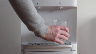 一个男人正在从饮水机里拿一杯冷水视频素材模板下载