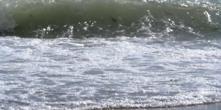 波浪在沙滩上涌动，白色的泡沫填满了屏幕，然后慢慢地退去又退去