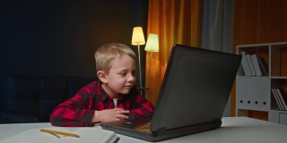学龄前儿童使用笔记本电脑在家进行在线教育。孩子们喜欢在网上做作业，回答电子设备屏幕上的问题。