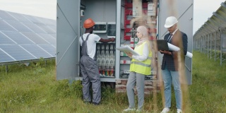 电气系统设备配电柜。多种族的人们审视绿色能源的生产过程。电力变压器。多种族的人在检查太阳能电站的开关