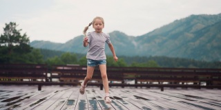 金发碧眼的孩子在雨后的木板甲板上奔跑玩耍