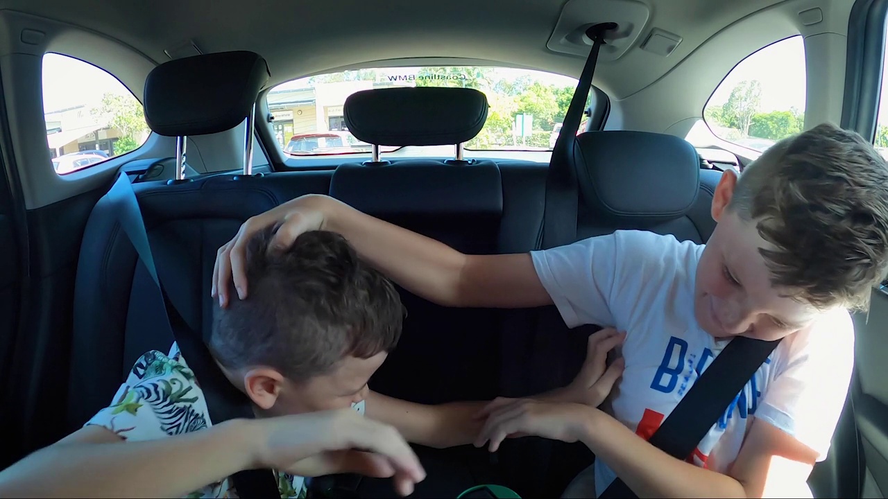 顽皮的男孩在汽车后座上互相碰撞。手臂和手的接触。