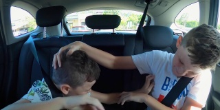 顽皮的男孩在汽车后座上互相碰撞。手臂和手的接触。