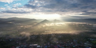 在雾天，当太阳升起的时候，无人机在山谷中乡村的城市景观