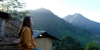 一个女人坐着喝咖啡，看着美丽的山景